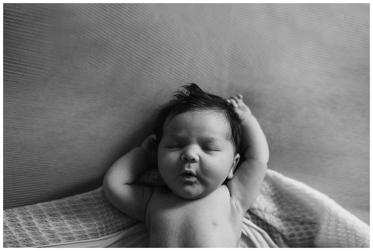Black and White image of a newborn baby stretching on the couch