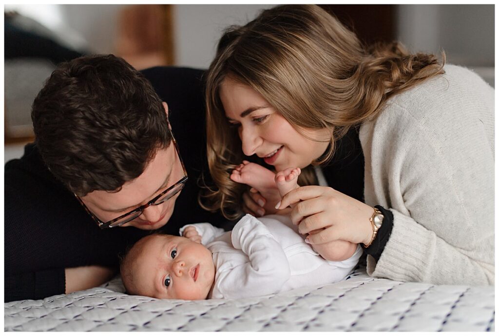 Family photographed on their bed playing with newborn baby girl