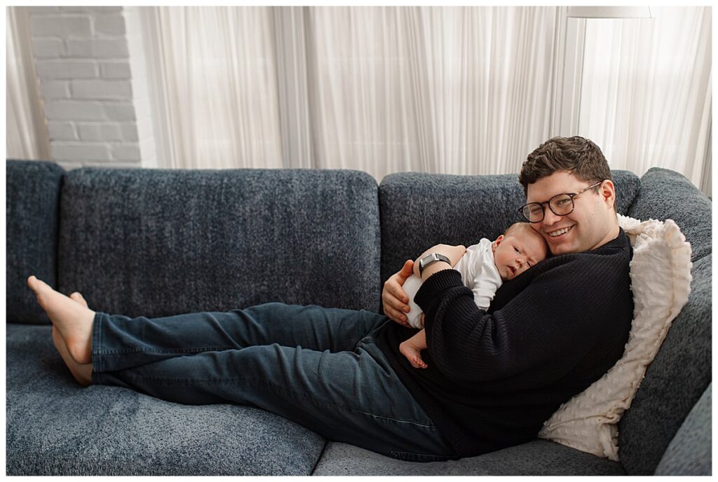dad holding newborn daughter on the couch